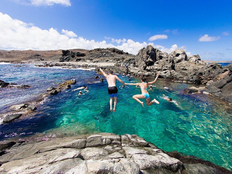 Conchi, the Natural Pool, seen from the rocks: a clear green basin walled off from the open sea by a black lava ridge
